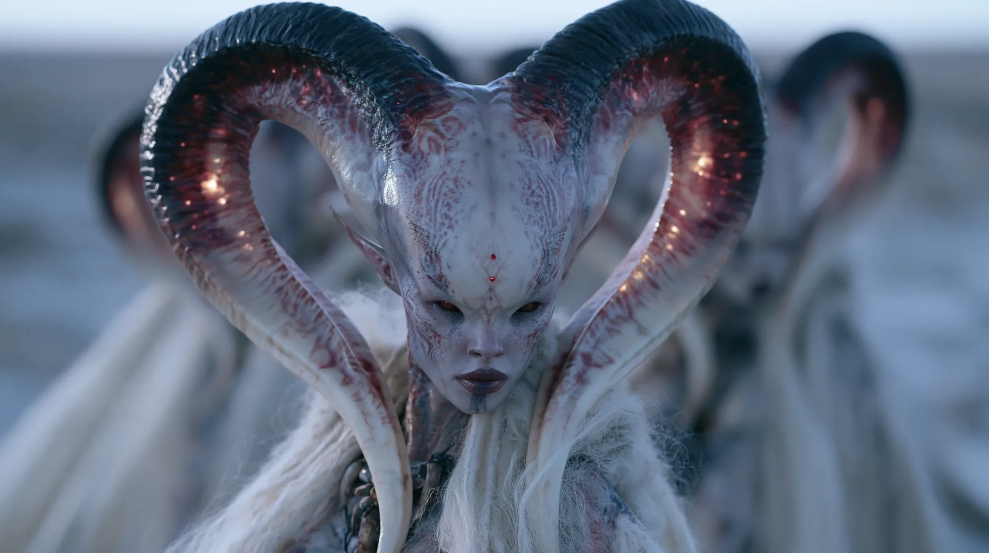 A pale being with great curling horns, dressed in white, before a grey sea with others behind.