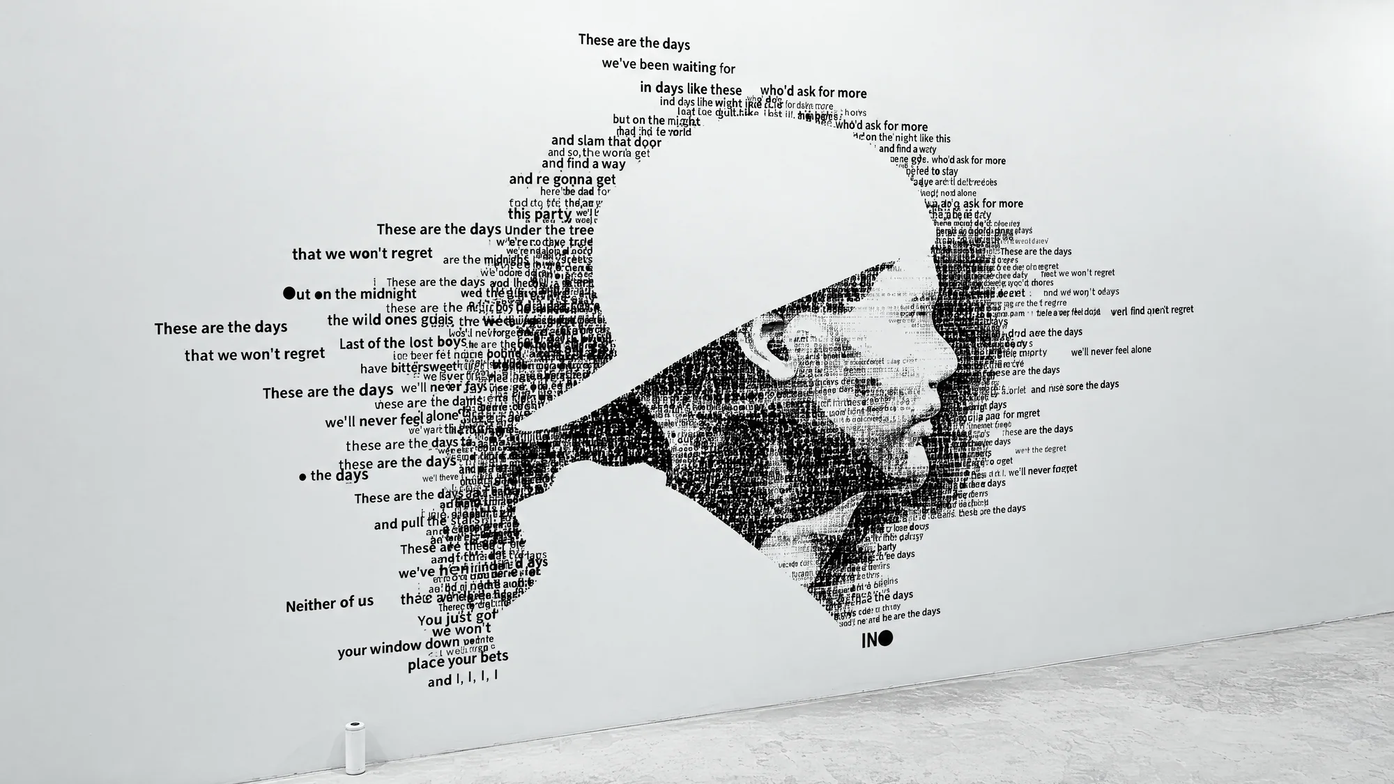 Avicii’s profile formed from black song lyrics on a white wall.