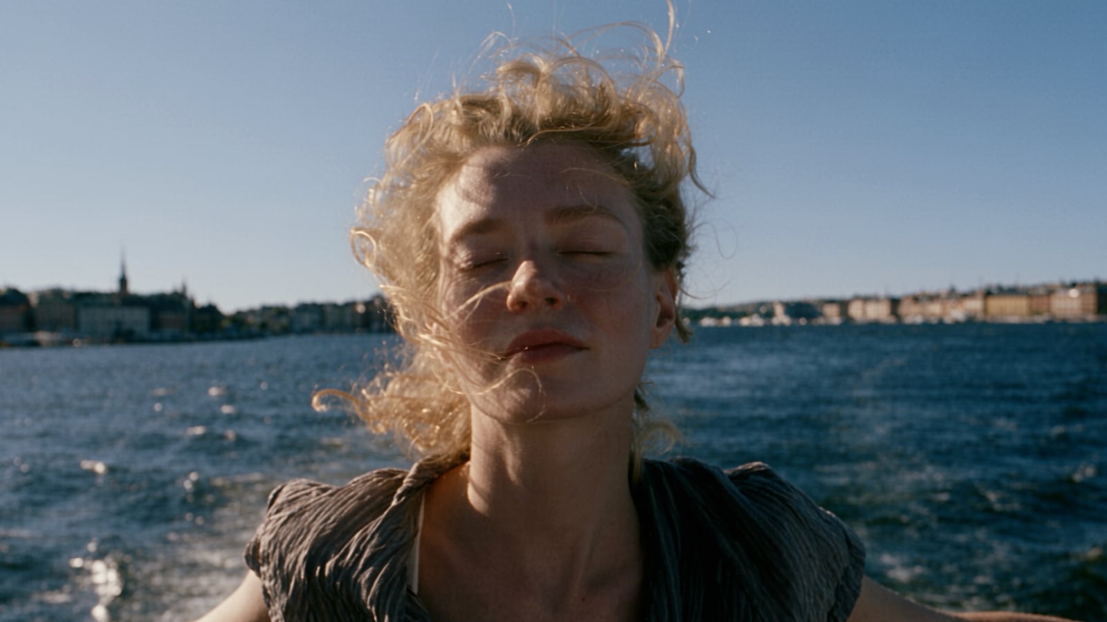 Source frame: a woman with wind-blown hair on a boat, a city skyline behind her